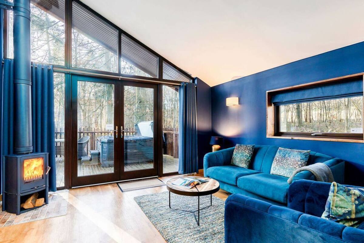 A modern living room with a blue sofa, a round coffee table, and a wood-burning stove.