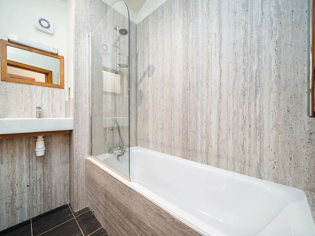 A bathroom with a bathtub, a shower, a sink, and a mirror.