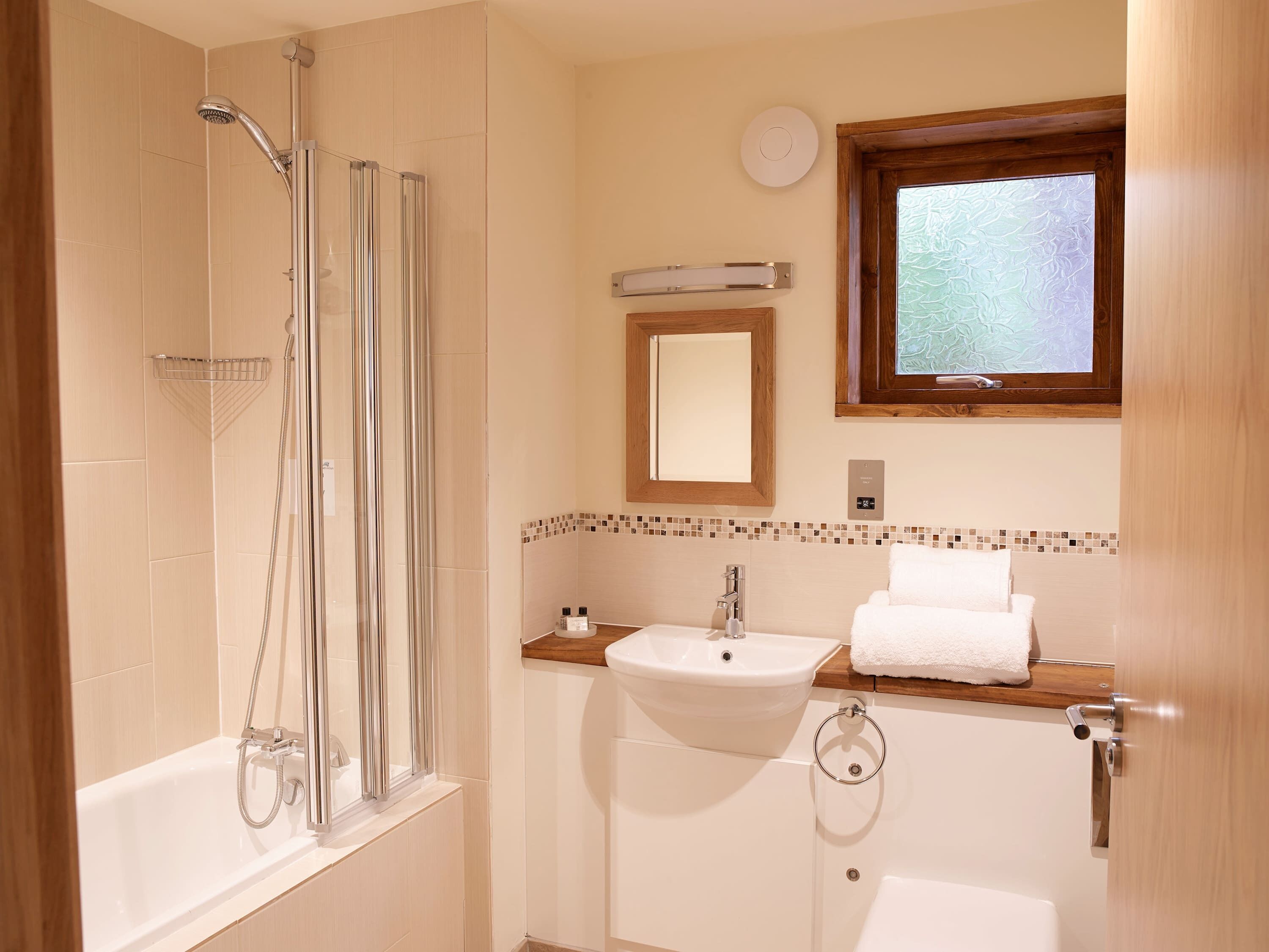 A bathroom with a shower, sink, and window.
