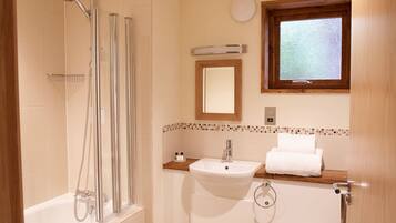A bathroom with a shower, sink, and window.