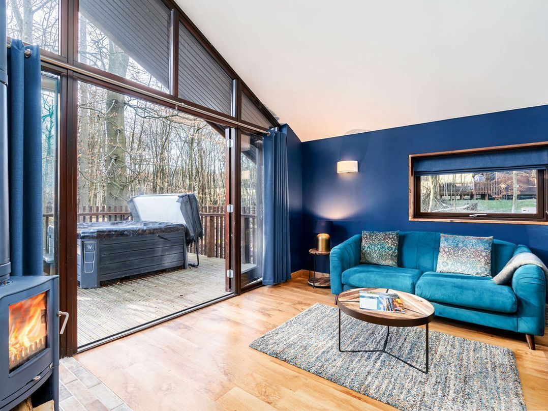 A modern living room with a fireplace, a blue sofa, and a large window.