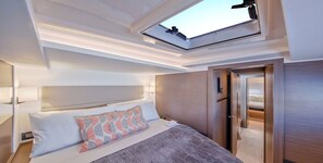 A modern hotel room with a skylight, a bed with patterned pillows, and a wooden headboard.