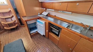 Una kitchenette compacta con refrigerador, horno y lavamanos.