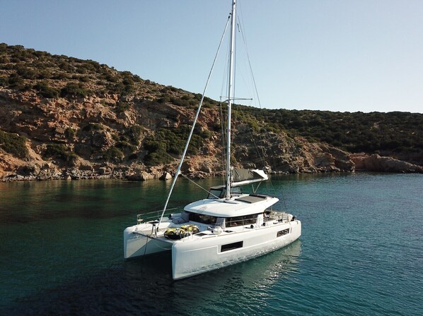 Eine weiße Yacht liegt an der felsigen Küste vor klarem Wasser.