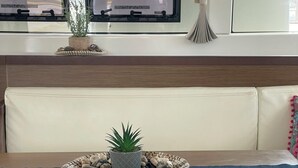 A modern kitchen with a built-in bench, a dining table, a white chair, and a potted plant. - Sun-Kissed Sailing Adventure in Islas Sarónicas (Alimos)