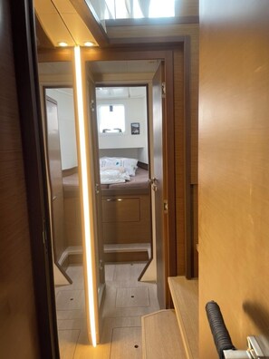 A narrow hallway leading to a bedroom with a bed, a window, and a small kitchenette area. - Sun-Kissed Sailing Adventure in Islas Sarónicas (Alimos)
