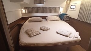 A compact, well-lit bedroom with a skylight, a bed with neatly arranged towels, and a small window. - Sun-Kissed Sailing Adventure in Islas Sarónicas (Alimos)