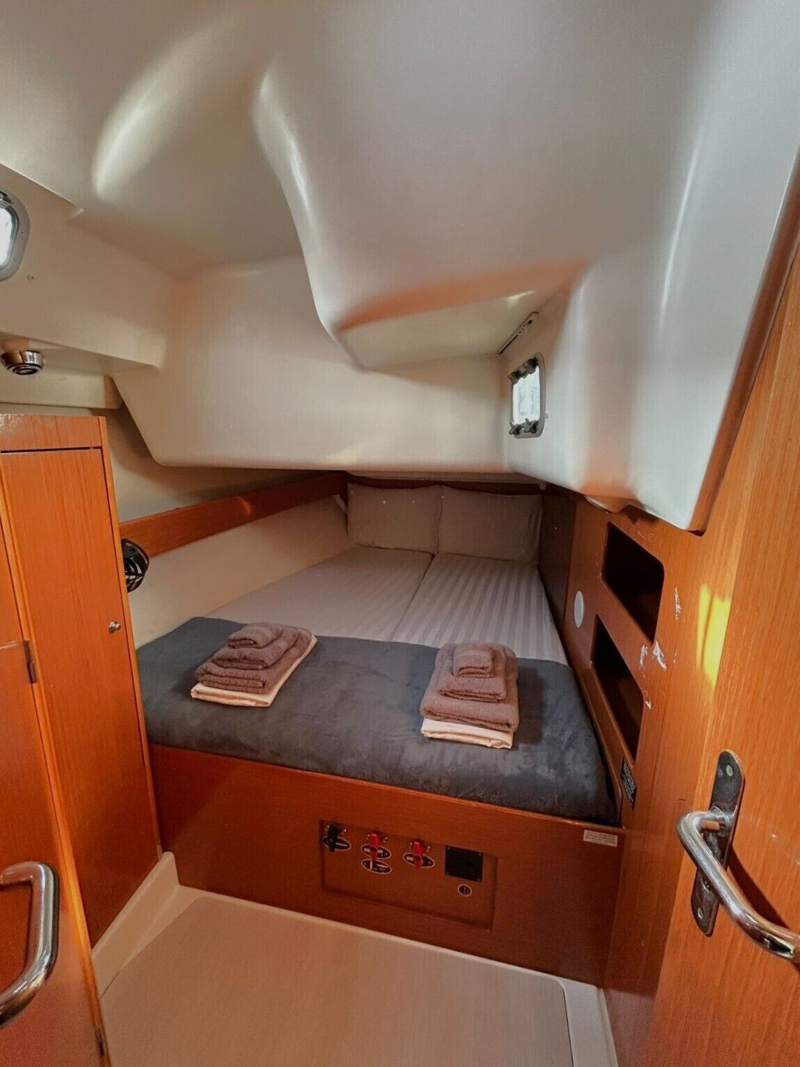 A compact cabin with a bed, a small window, and a control panel.