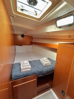 Une petite cabine équipée d’un lit superposé, d’une petite fenêtre et d’un puits de lumière.