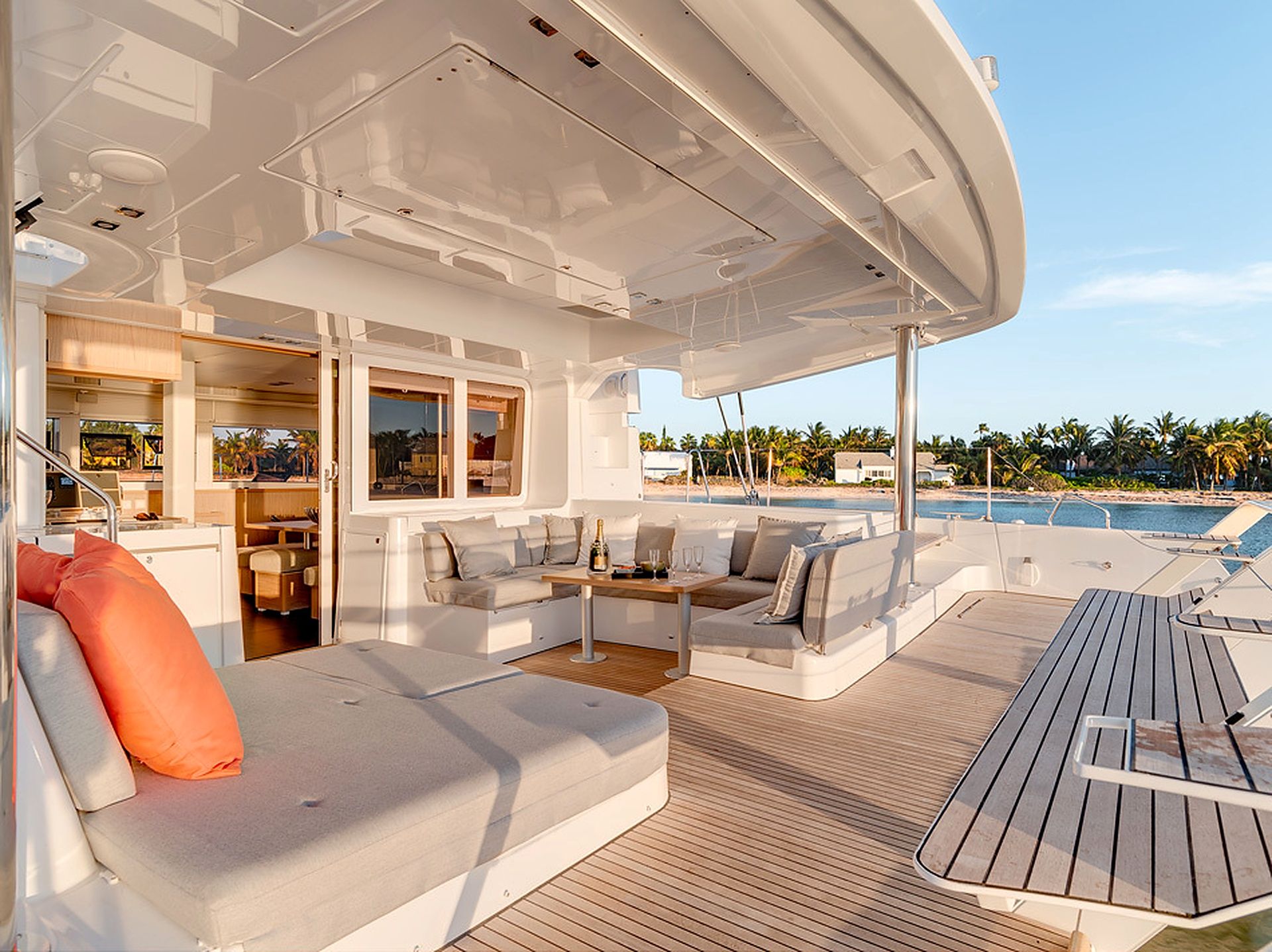A yacht's deck with a seating area, a dining table, and a view of the ocean.