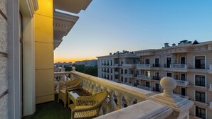 A balcony with wicker furniture, a view of adjacent buildings, and a clear sky.