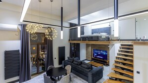 A modern living room with a sofa, chairs, a TV, and a staircase.