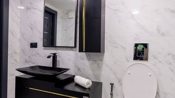 Une salle de bain moderne avec un meuble-lavabo noir, des toilettes blanches et un sol carrelé en marbre.