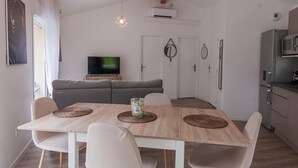 Ein modernes Wohnzimmer mit Fernseher, Sofa, Esstisch und Küchenzeile.