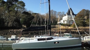 A white yacht docked at a marina with a stone wall and trees in the background. - Sun-Kissed Sailing Adventure in Golfo de Morbihan, Brittany (La Trinité-sur-Mer)
