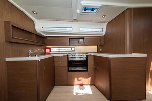 A compact kitchen with wooden cabinetry, a built-in oven, and a window above the sink. - Sun-Kissed Sailing Adventure in Zadar, Croatia (Zadar)