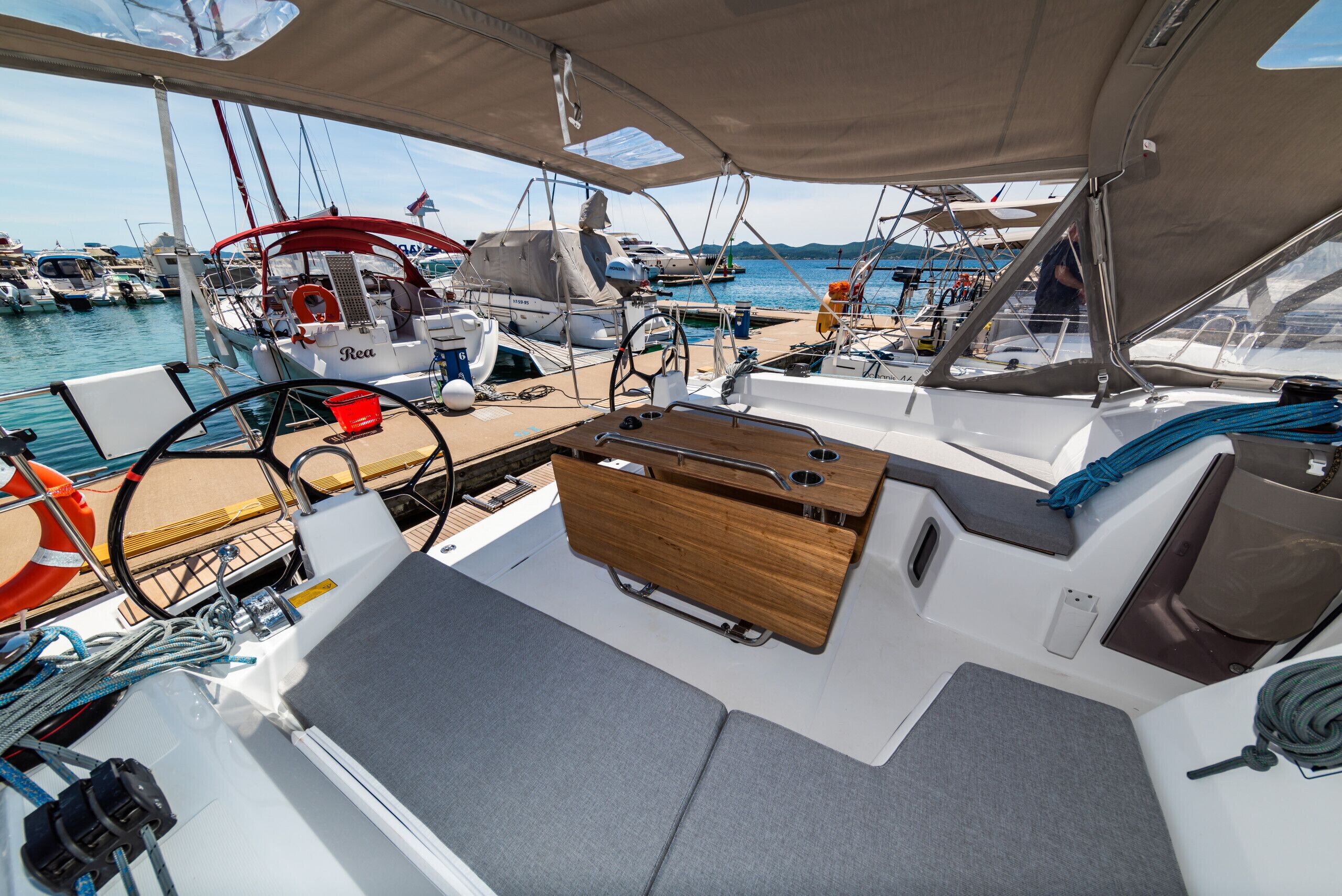 A boat deck with seating, a steering wheel, and a life preserver.