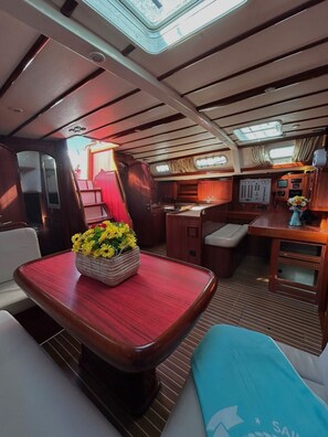A compact, well-lit interior with a dining area, kitchenette, and seating. - Sun-Kissed Sailing Adventure in Islas Sarónicas (Alimos)