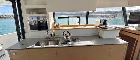 A compact kitchen with a gas stove, sink, and a window overlooking a body of water.