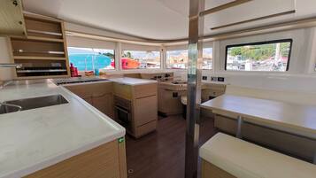 Cocina compacta con lavamanos, estufa y encimera, además de un comedor con un banco.