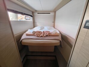 Una habitación pequeña y estrecha con una cama, una ventana y una puerta.