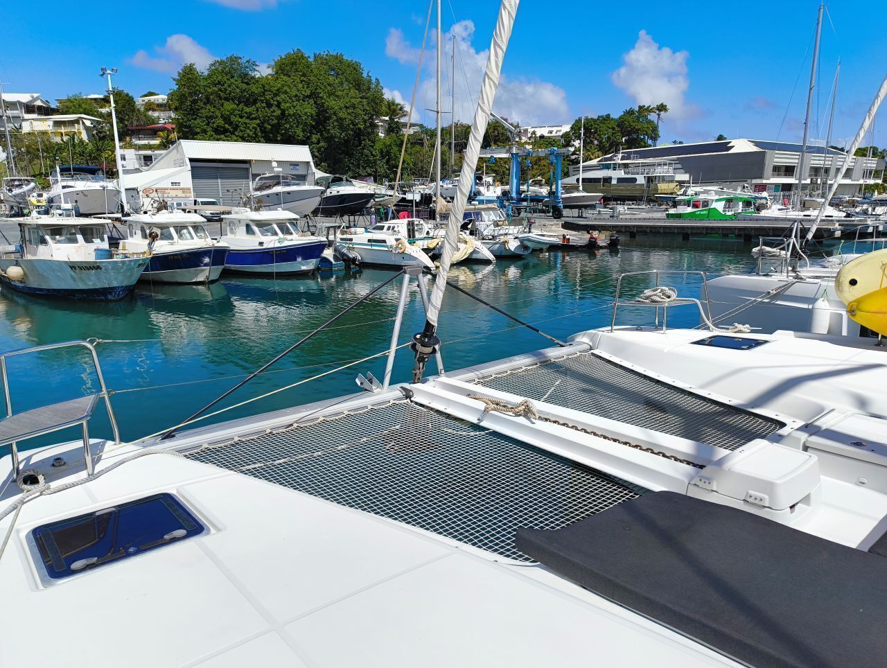 Ein Yachthafen mit mehreren angedockten Booten, blauem Himmel und Gebäuden im Hintergrund.