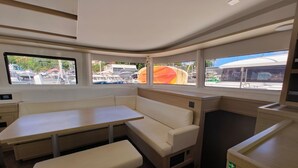 Ein kompakter Innenraum mit Tisch und Sitzbank, einer kleinen Küchenzeile und Fenstern mit Blick hinaus.