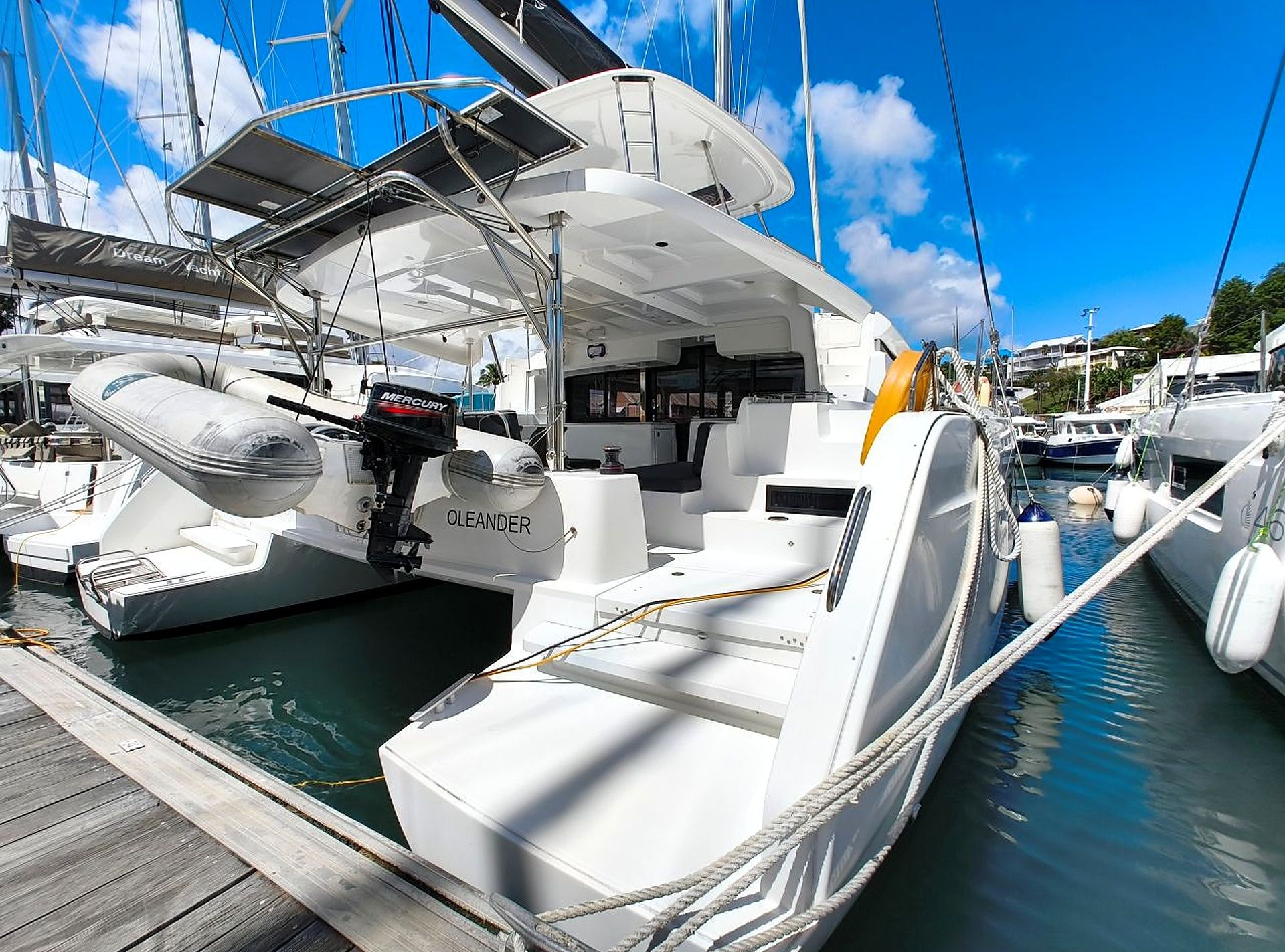 A white yacht docked at a marina with a Mercury outboard motor, a white deck, and a cabin area.