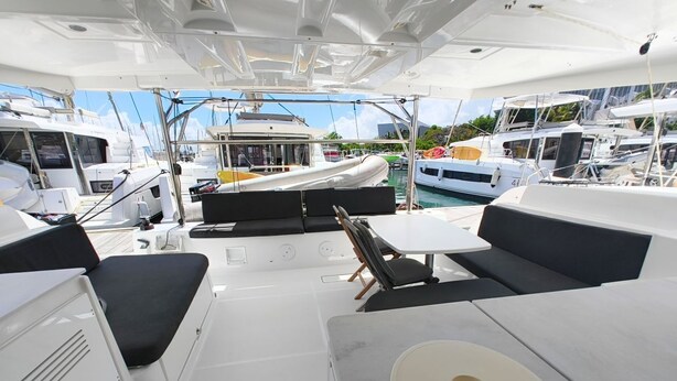 Ein Bootsdeck mit Sitzgelegenheiten, einem Tisch und Blick auf andere Boote im Hafen.