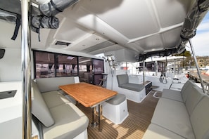 A boat interior with a table, seating, and a view of the marina. - Sun-Kissed Sailing Adventure in Zadar, Croatia (Zadar)