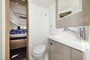A compact bathroom with a white toilet, a sink with a chrome faucet, and a mirror above the sink.