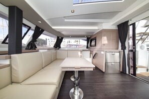 A modern interior with a sofa, table, and kitchenette. - Sun-Kissed Sailing Adventure in Zadar, Croatia (Zadar)