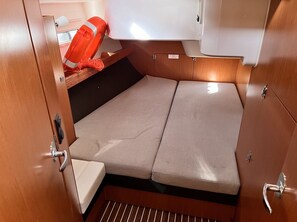 Interior pequeño y bien iluminado con un banco de madera, una zona de descanso acolchada y un flotador en una estantería.