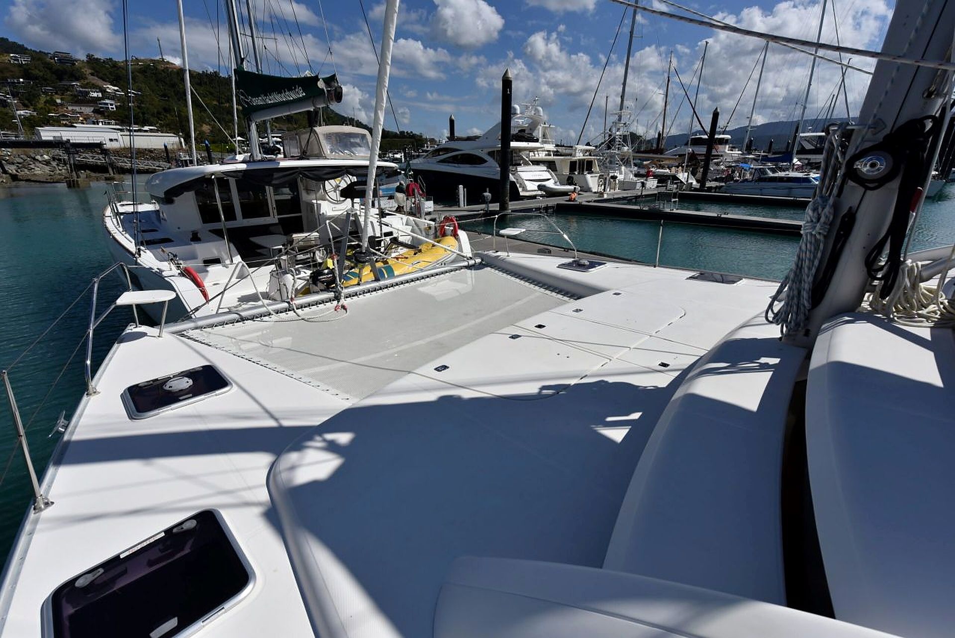 A marina with multiple boats docked, a clear sky, and a calm sea.