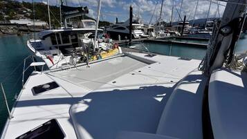 A marina with multiple boats docked, a clear sky, and a calm sea.