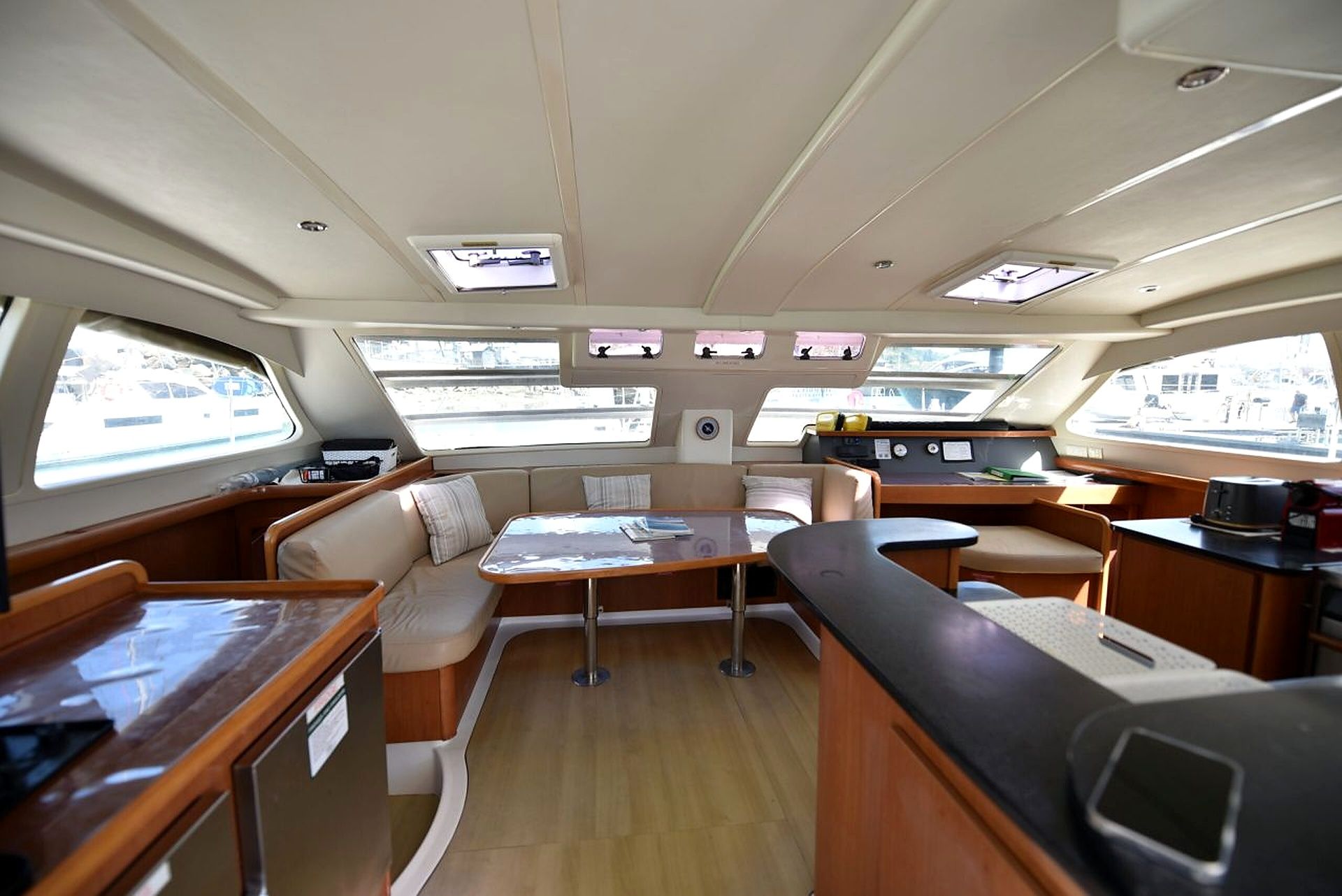 A boat interior with a dining area, seating, and a control station.