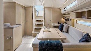 A compact interior with a dining table, seating area, and a small kitchenette. - Caribbean Bliss: Sun-soaked Sailing Adventure from Granada, San Jorge (Saint George's)