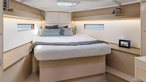 A compact, well-lit bedroom with a bed, bedside tables, and built-in shelves. - Caribbean Bliss: Sun-soaked Sailing Adventure from Granada, San Jorge (Saint George's)
