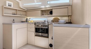 A compact kitchen with a built-in oven, stainless steel appliances, and light wood cabinetry.
