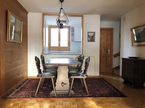 A dining area with a wooden table and chairs, a hanging light fixture, and a view through a window. - Oberland Nr. 29 Appartement/Fewo, Dusche oder Bad, WC 6-Bettwohnung by Interhome (Gstaad)
