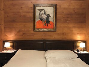 A hotel room with a wooden headboard, a bed with white linens, two bedside lamps, and a framed artwork on the wall. - Oberland Nr. 29 Appartement/Fewo, Dusche oder Bad, WC 6-Bettwohnung by Interhome (Gstaad)