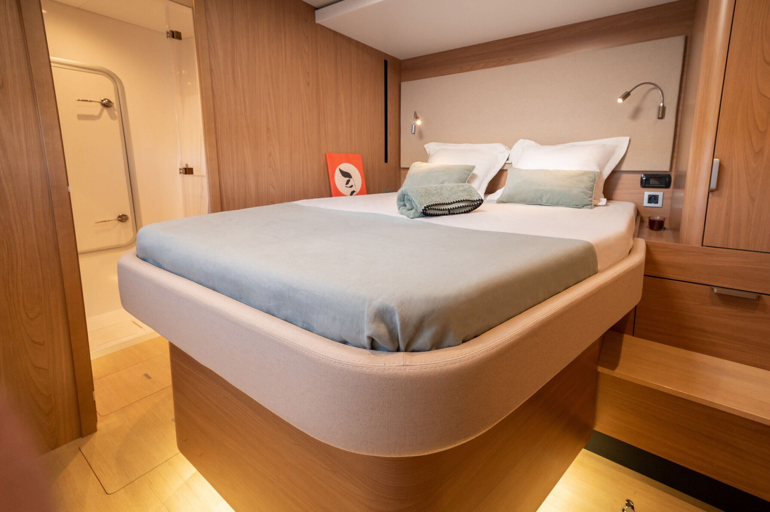 Ein modernes Hotelzimmer mit einem bogenförmigen Bett, Holzvertäfelung, einem Nachttisch und einer Nachttischlampe.