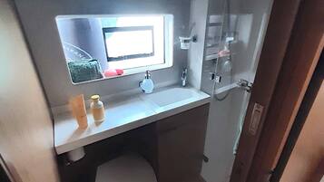 Une petite salle de bain comprenant des toilettes, un lavabo avec un miroir et une douche.