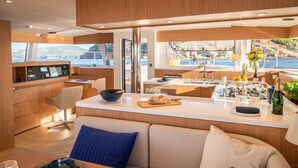 Et moderne køkken med en central ø, et spiseområde med en sofa og havudsigt.