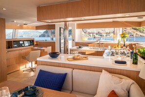 Eine moderne Küche mit einer zentralen Kochinsel, ein Essbereich mit einer Couch und Meerblick.