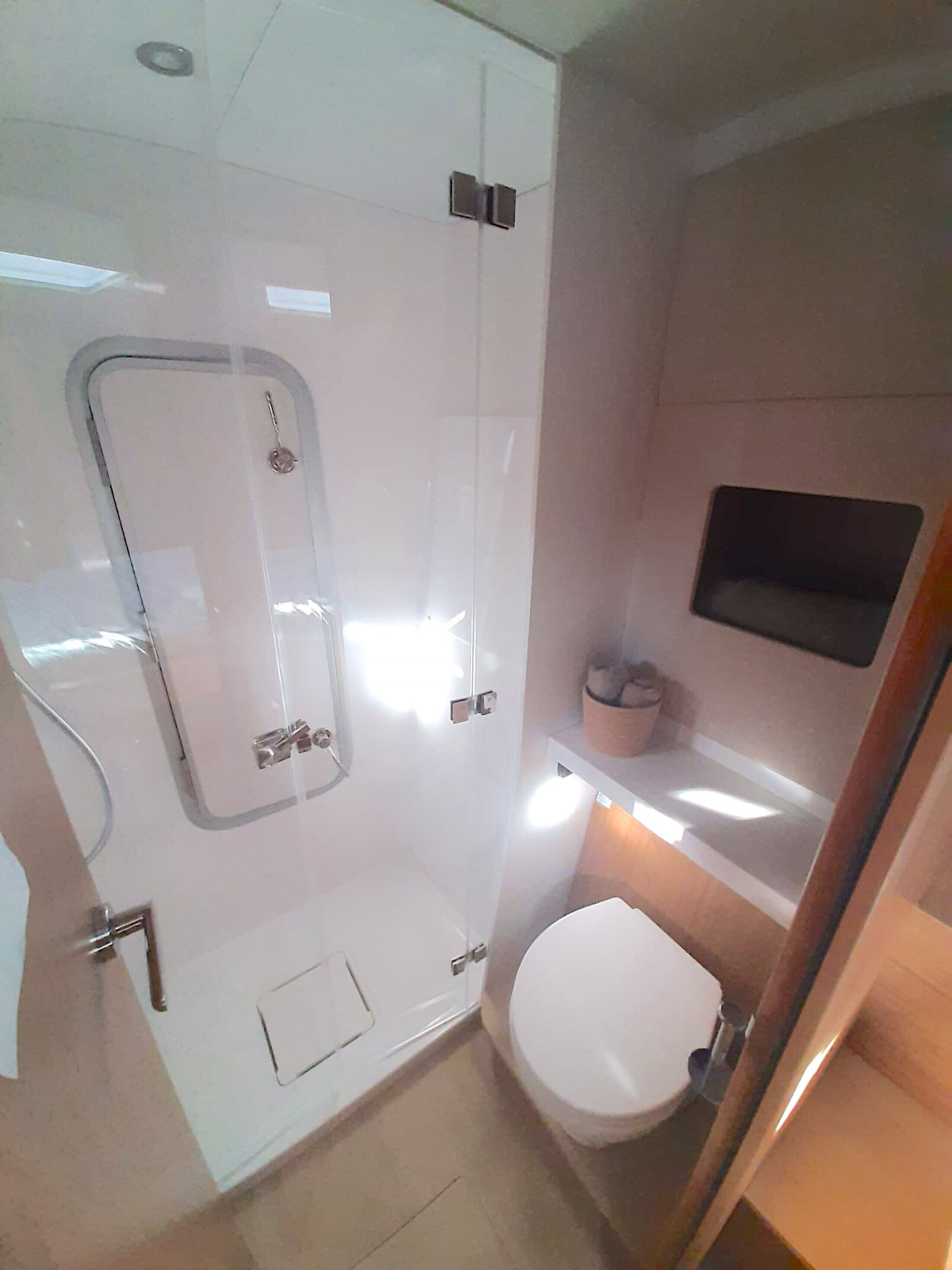 Ein kleines Badezimmer mit Duschkabine, Toilette und Ablagefläche für Toilettenartikel.
