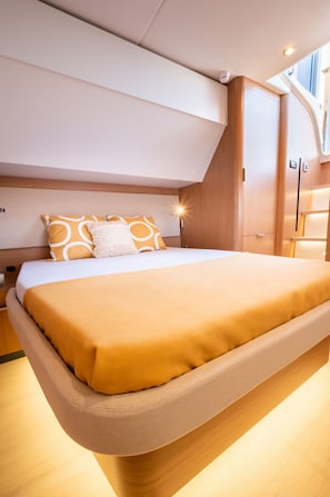 A modern bedroom with a large bed, wooden headboard, and a skylight.