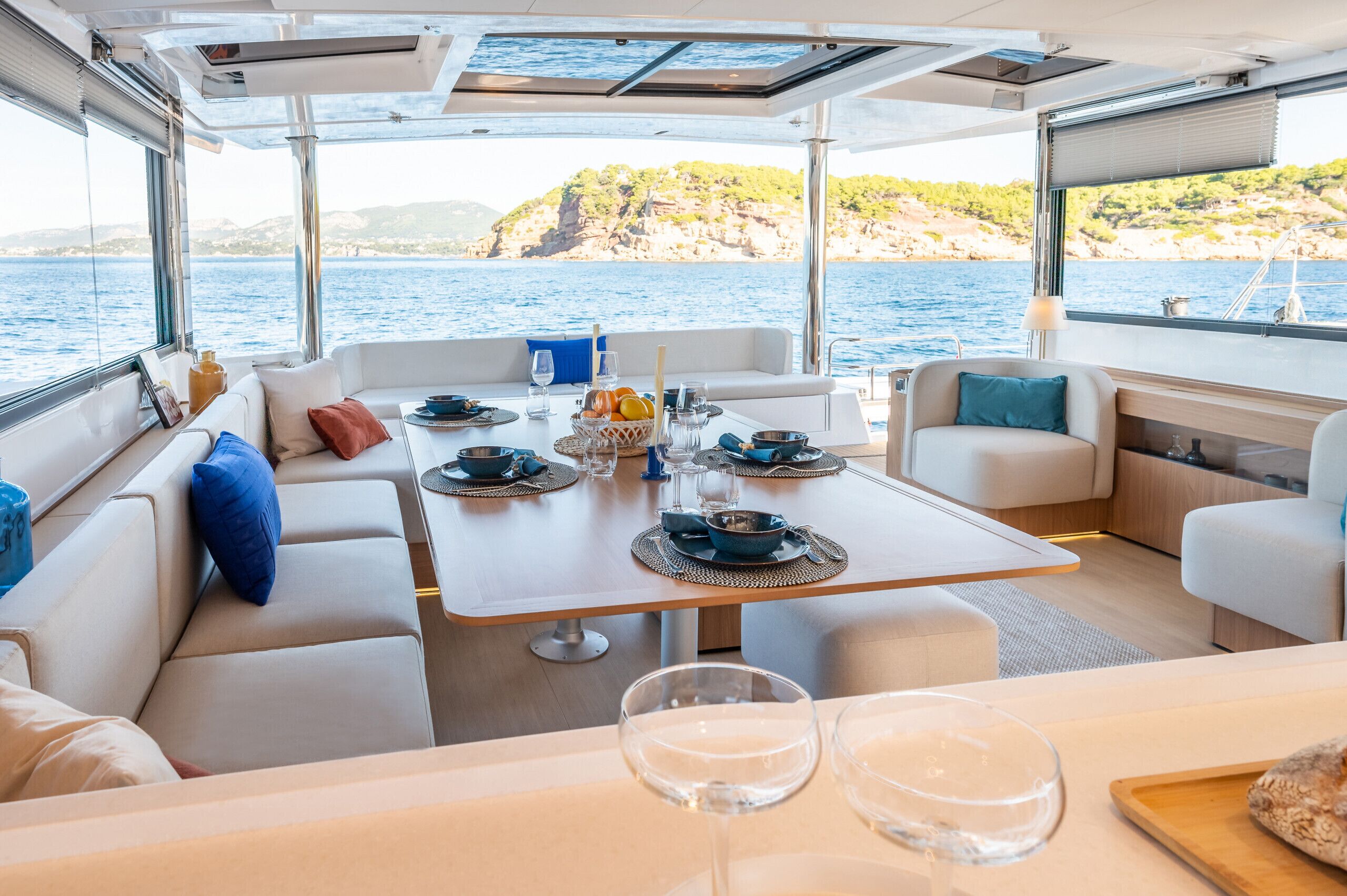 Schiffsinnenraum mit Essbereich, Sitzgelegenheiten und Blick auf das Meer.