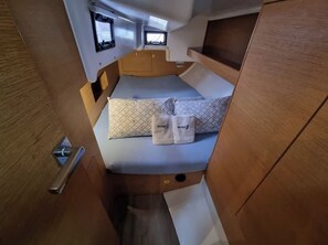 A compact, well-lit cabin with a bed, a small window, and a built-in TV.