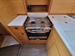 A compact kitchen with a stove, oven, and wooden cabinets.